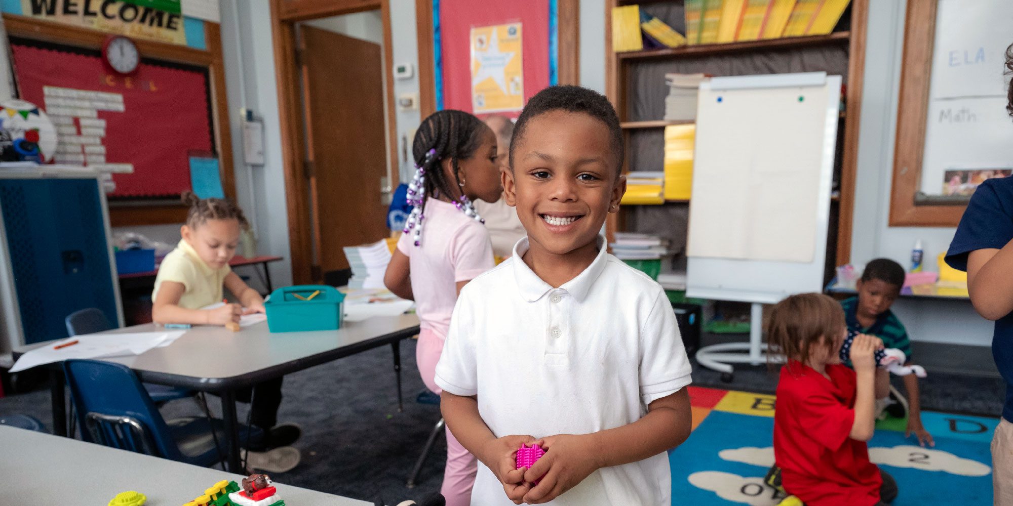 Smiling student in a busy STEAM Academy of Warren classroom.
